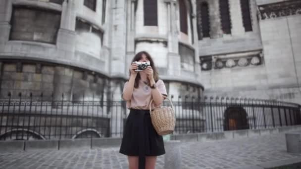 Hermosa joven de pelo oscuro, vestida con pantalones cortos negros y una camiseta beige, toma fotos de la ciudad. Retrato de izquierda a derecha en tiempo real . — Vídeos de Stock