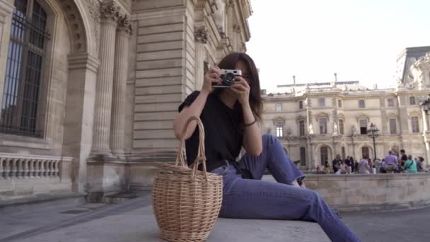 Красивая молодая женщина с темными волосами, в джинсах и черной футболке фотографирует город. Снимок портрета слева направо в реальном времени . — стоковое видео