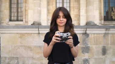 Film kameralarını geri seven fotoğraf çeken genç kadın. Arka planda Paris'te eski binalar