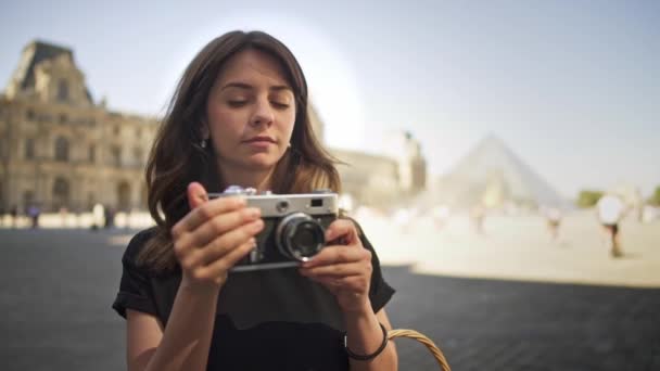 PARIS, FRANÇA, ABRIL 2019. Lento movimento jovem mulher fazendo foto com uma câmera de filme no fundo do museu do Louvre — Vídeo de Stock