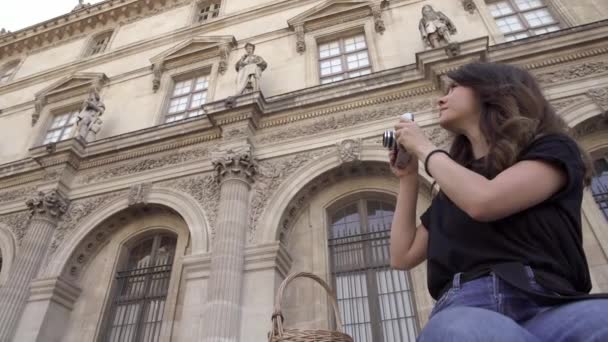 Die schöne junge Frau mit dunklen Haaren, Jeans und schwarzem T-Shirt fotografiert die Stadt. von links nach rechts schwenken Echtzeit-Portraitaufnahme. — Stockvideo