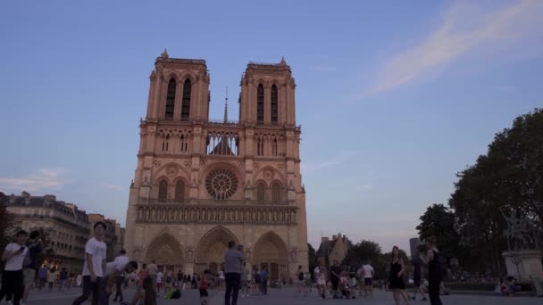 프랑스 파리 - 2019년 6월 17일: 석양을 바라보며 노트르담 드 파리의 사진을 실시간으로 촬영합니다. 고딕 양식의 노트르담 노트르담 드 파리 근처 관광객의 군중. — 비디오