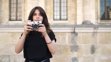 Paris, Fransa Güzel kadın bir film kamera ile fotoğraf yapma. Arka planda Paris'te eski binalar
