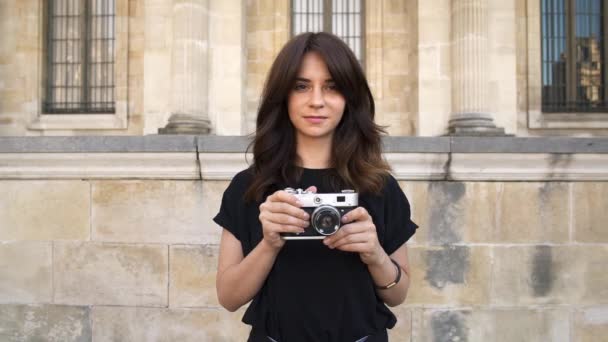 Young woman making photo rewinding a film camera on background of old buildings in Paris — Stock Video