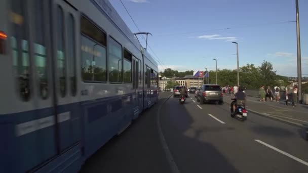 Цюрих, SWITZERLAND - апрель 2019: Gimbal shot of tram and cars passing on bridge in Zurich — стоковое видео