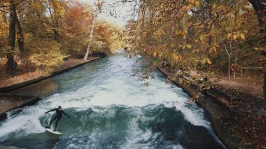 Münih, Almanya, 18 Kasım 2019: Eisbach nehri üzerinde bir dalga urban surfers gerçek zamanlı çekim. Münih English Garden'da Nehir Sörfü, Münih, Almanya.