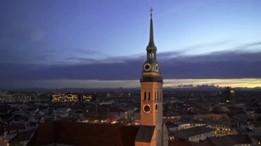 Münih, Almanya - 25 Kasım 2019: Münih şehrinin ve akşam saatlerinde St. Peters Kilisesi saat kulesinin güzel manzarası. Gerçek zamanlı orta atış, Almanya.