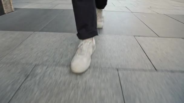 View from ground level of white men sneakers walking along pavement — Stock Video