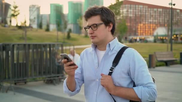 Uomo adulto medio che cammina con uno smartphone nel grande parco della città — Video Stock