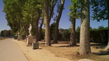 Baharın güneşli bir gününde Versailles Bahçeleri 'nin dar sokaklarında çekilen düşük açılı takip aracı.