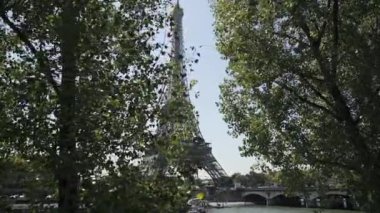  Mavi gökyüzünün arka planındaki yeşil ağaçlardan Eyfel kulesinin yuvarlanan görüntüsü.