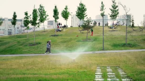 Muchas personas y niños en el parque de la ciudad dando un paseo durante un día de verano — Vídeos de Stock