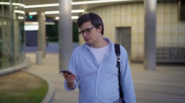 Gözlüklü ve mavi tişörtlü bir adamın orta pozu telefonu kapatıyor.