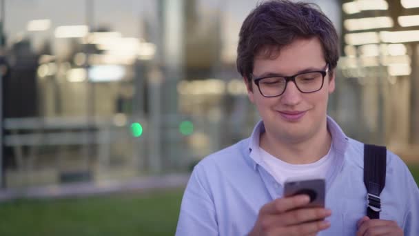Első nézet portré fiatal férfi gépelés mobiltelefon a szabadban — Stock videók