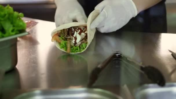 Handheld schot van chef-kok handen in witte handschoenen afwerkingen maken doner in pita — Stockvideo