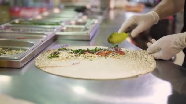 Handheld schot van chef-kok handen in witte handschoenen maken doner in pita — Stockvideo