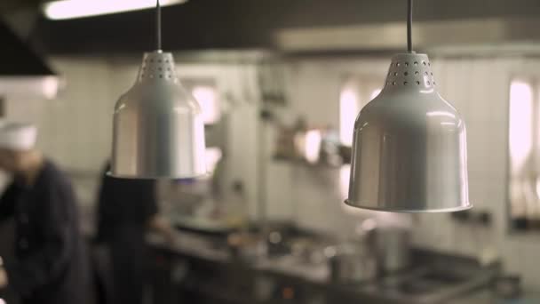 Sluiten van de lampen in de keuken restaurant met chef-koks op de achtergrond — Stockvideo