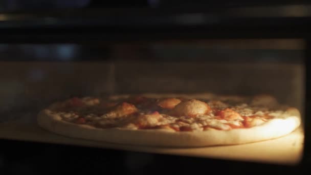 Ruční zblízka pohled na pečení sýrové pizzy v troubě