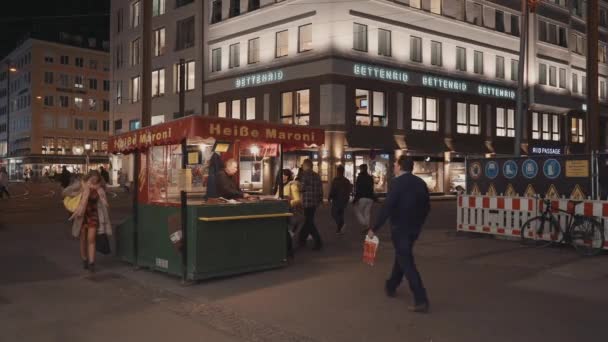 München, Tyskland - 26 november 2019: Real time wide shot of people passing by the stall with food on the street in München at evening time, München, Tyskland — Stockvideo