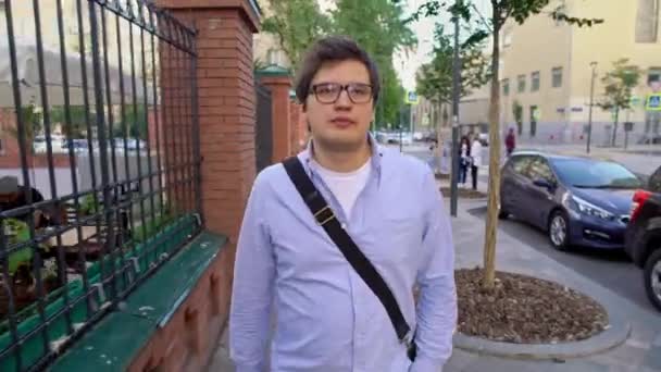 Meio tiro de homem em óculos e camisa azul andando ao longo da rua — Vídeo de Stock