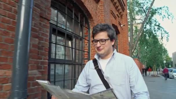 Gimbal portrait de l'homme souriant touriste avec carte sur fond ville bouleau rouge bâtiment — Video