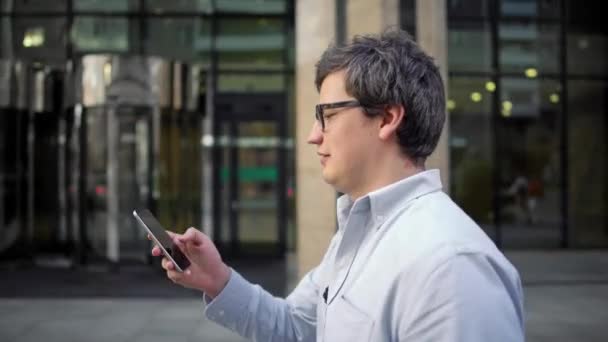 Perfil de retrato plano de hombre en gafas y camisa azul caminando por la calle — Vídeos de Stock