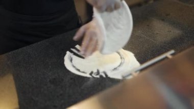 Aşçının üst görüntüsü pizza hamurunu yemek masasına gerer.
