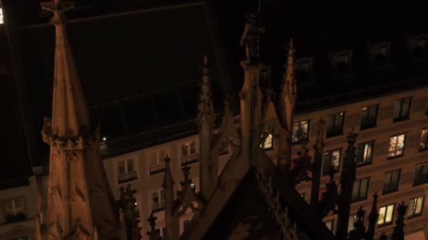 MUNICH, ALEMANIA - 26 de noviembre de 2019: Panorama de izquierda a derecha en tiempo real plano de las ventanas de la casa con el nuevo ayuntamiento por la noche, Munich, Alemania . — Vídeo de stock
