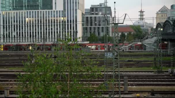 MNICHOV, NĚMECKO - 25. června 2018: Panoramatický záběr červeného vlaku pohybujícího se pod hackerským mostem na centrálním nádraží v Mnichově — Stock video