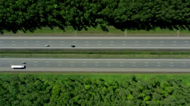 緑の木々に囲まれた複数の車線の道路、高速道路のドローン空撮のパンショット — ストック動画