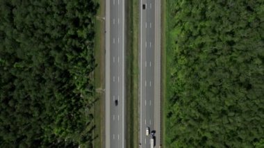 Çevresi yeşil ağaçlarla çevrili çok şeritli yollar, bir otoban insansız hava aracının üzerinden uçar.