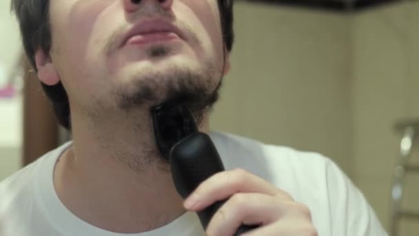 Young man with a beard shave stubble with electric razor — Stock Video