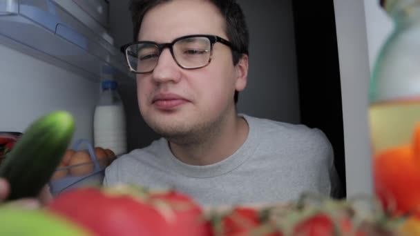 Мужчина открывает холодильник рано утром, берёт яблоко — стоковое видео