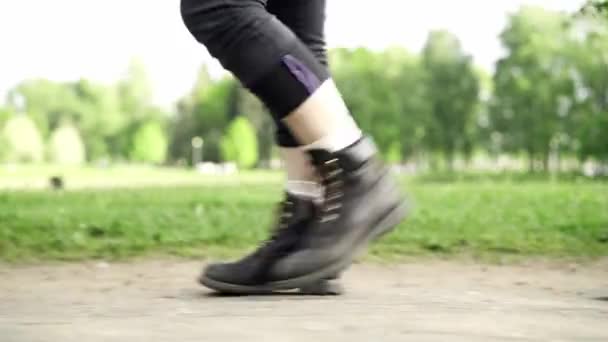 穿着靴子的腿在城市公园的背景上行走，侧面中弹 — 图库视频影像