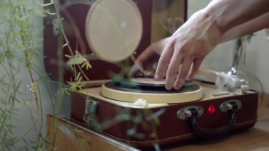 Eller bir oyuncuya vinil disk takıyor, pan shot.
