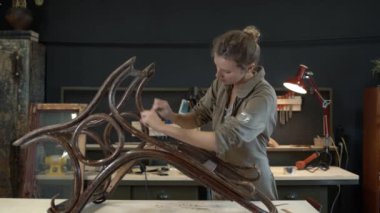 Bir atölyede ahşap sallanan sandalyenin restorasyonu, bayan restoratör.