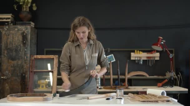 Jonge vrouw polijsten een houten detail in werkplaats — Stockvideo