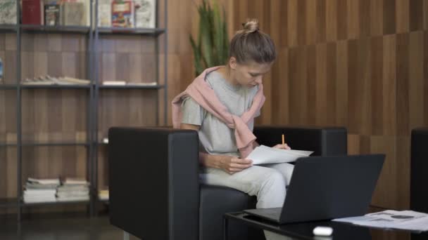 Γυναίκα που εργάζεται στη βιβλιοθήκη με φορητό υπολογιστή — Αρχείο Βίντεο