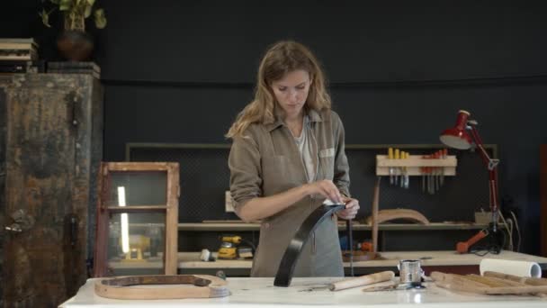 Giovane donna che dipinge un dettaglio in legno in officina — Video Stock
