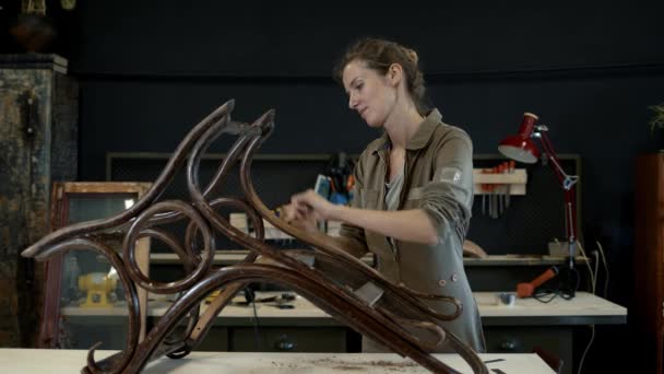 Restauración de mecedora de madera en un taller, restaurador femenino — Vídeos de Stock