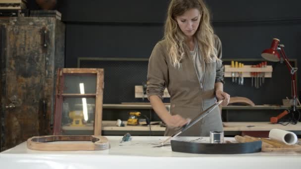 Mujer joven puliendo un detalle de madera en el taller — Vídeo de stock