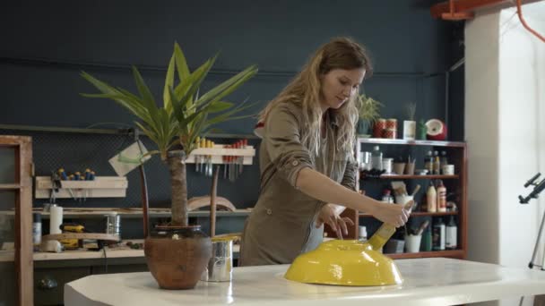 Een vrouwelijke restaurateur schildert een geel detail in werkplaats — Stockvideo