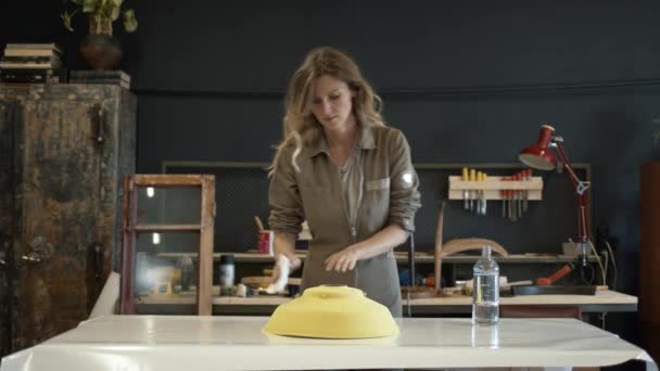 Een vrouwelijke restaurateur polijsten een geel detail — Stockvideo