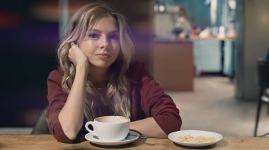 Kafede rüya gören ve toplantı bekleyen çekici, güler yüzlü bir kadın. Doğrudan kameraya bakıyor. İşaret fişeği