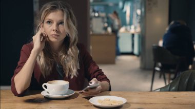 Kafedeki çekici kadın internette akıllı telefon kullanıyor ve arkadaşlarıyla buluşmayı bekliyor.. 