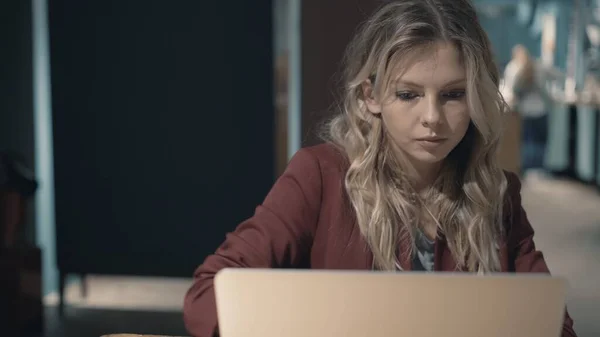 Aantrekkelijke zakenvrouw in cafe surfen op het internet met behulp van laptop en wachten op een ontmoeting met een vriend. — Stockfoto