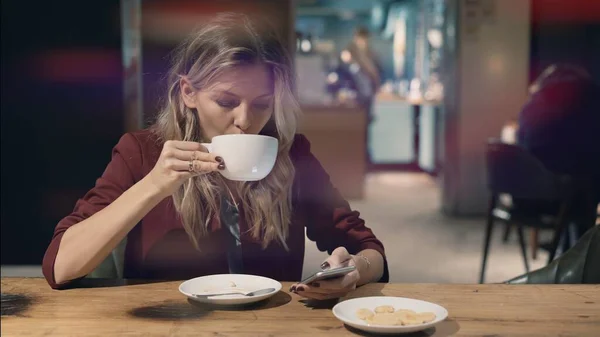 Mujer atractiva en la cafetería navegando por Internet utilizando el teléfono inteligente y esperando alguna reunión con un amigo. Bengala de lente — Foto de Stock