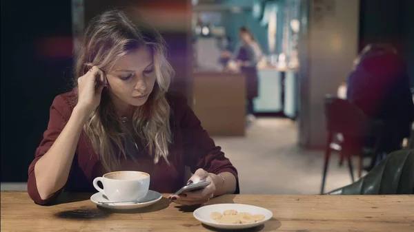 Mujer atractiva en la cafetería navegando por Internet utilizando el teléfono inteligente y esperando alguna reunión con un amigo. Bengala de lente — Foto de Stock