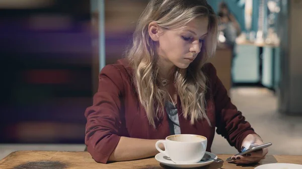 Aantrekkelijke vrouw in cafe surfen op het internet met behulp van een smartphone en wachten op een ontmoeting met een vriend. Geurvlam — Stockfoto