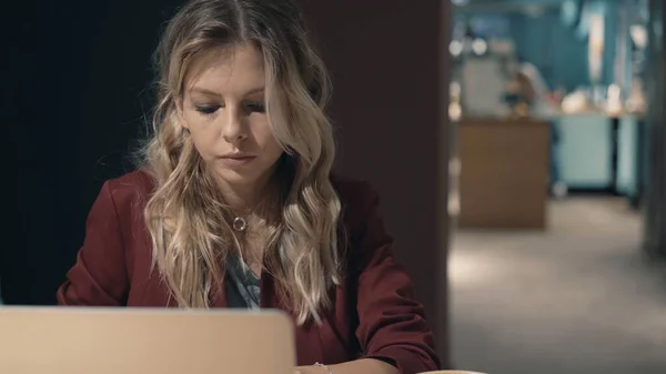 Aantrekkelijke zakenvrouw in cafe surfen op het internet met behulp van laptop en wachten op een ontmoeting met een vriend. — Stockfoto